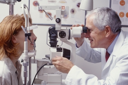 Male Optometrist Performing Eye Exam on Middle-Aged Woman